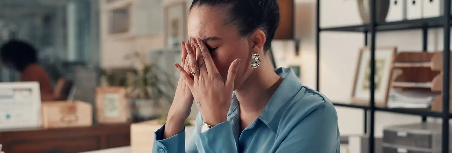 A woman sitting at a desk and looking stressed.