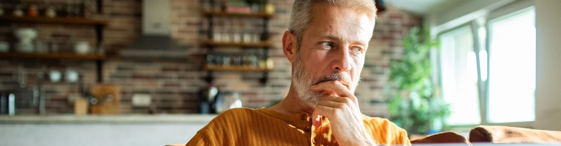 A man in his 50s thinking while using a laptop