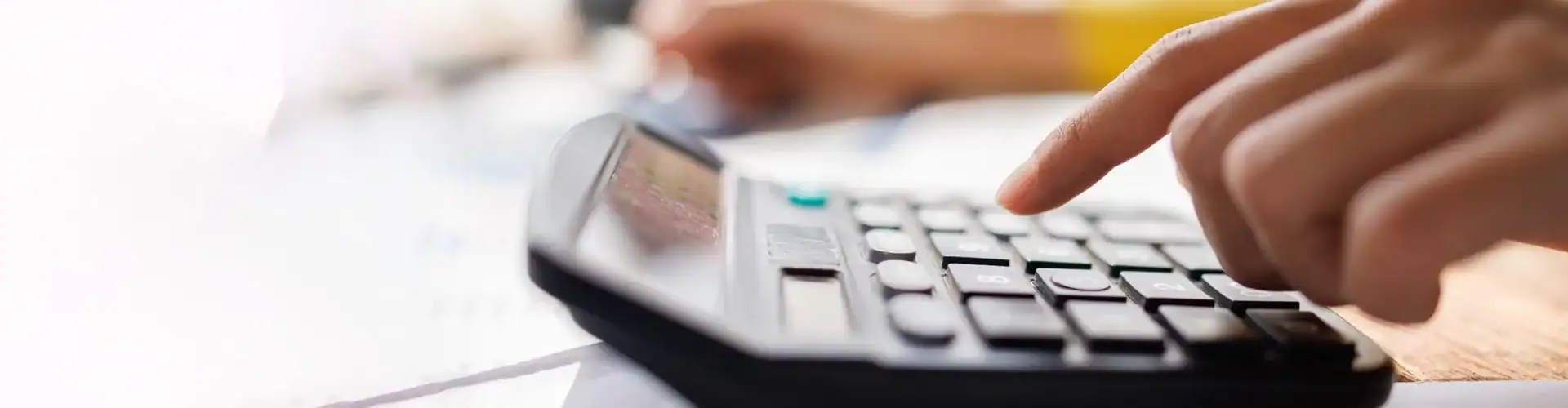 A person using a calculator while reviewing paperwork.